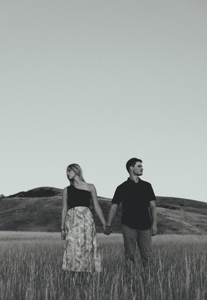 Black and white photo of couple holding hands in field